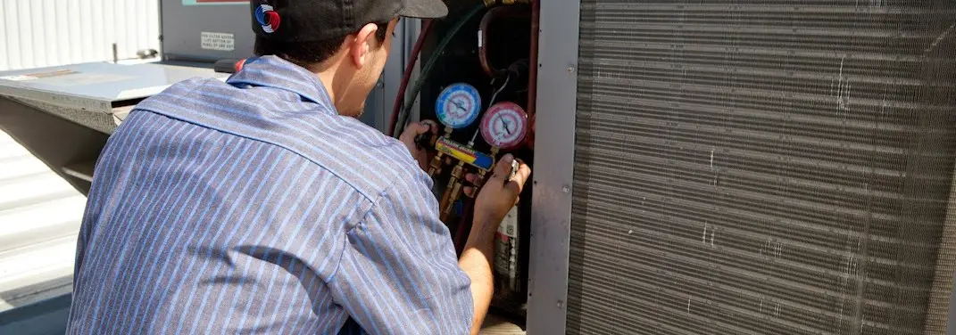 HVAC technician servicing a condenser unit in Essex